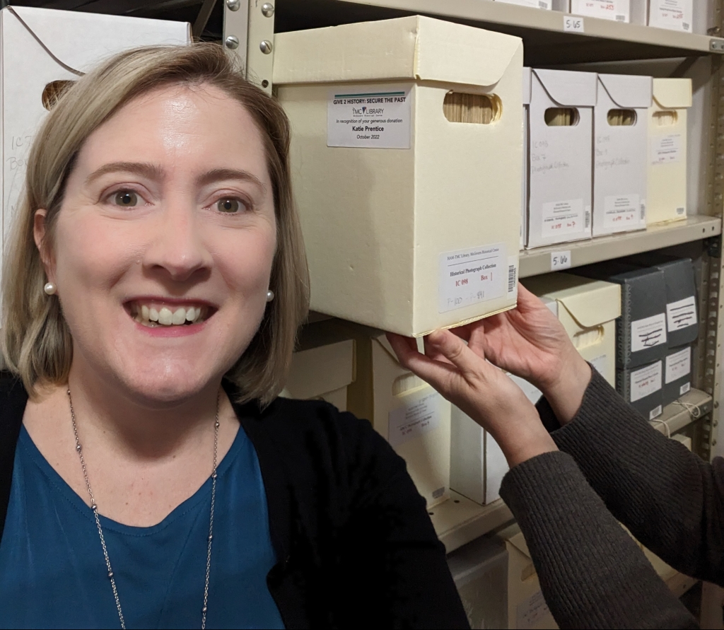 Katie Prentice, Executive Director of the TMC Library, takes a selfie with her adopted box. Your selfie can be taken with or without Archivist Hands.