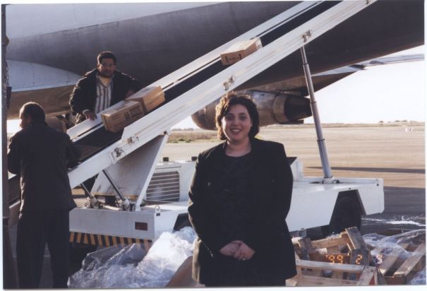 Debbie Goldberg, Executive Director of Texas Hadassah Medical Research Foundation, stands as medical supplies are unloaded from plane behind her at Yasser Arafat International Airport in Gaza on February 9, 1999. [IC 105 Texas Hadassah Medical Research Foundation records, McGovern Historical Center, TMC Library, IC105-024]